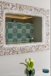 a mirror on a wall with a vase of flowers at Aradi Apartman in Pécs