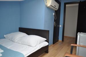a bed with white pillows and a blue wall at Hotel Your Comfort in Tbilisi City