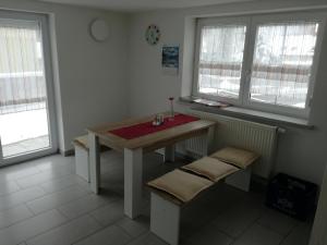 a kitchen with a wooden table and two windows at Pension am Kirchberg in Wehringen