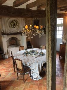een eetkamer met een tafel met stoelen en een kroonluchter bij La Moulinière, jolie longère du XVIIè in La Jaille-Yvon