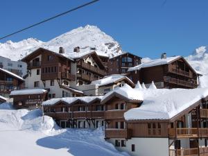 een groep gebouwen bedekt met sneeuw met een berg bij Résidence l'Oxalys in Val Thorens