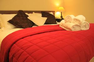 un letto rosso con asciugamani e cuscini sopra di Annandale Arms Hotel a Moffat