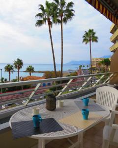 a table on a balcony with palm trees and the ocean at Casa Lea in Ventimiglia