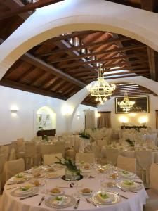 un salón de banquetes con mesas y sillas blancas y una lámpara de araña en Masseria Protomastro Hotel en Gravina in Puglia