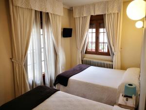 a bedroom with two beds and a window at Hostal Alcántara in Ávila