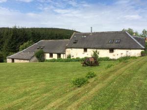 a large white house with a grass field in front of it at Parkmore Holiday Cottages in Dufftown