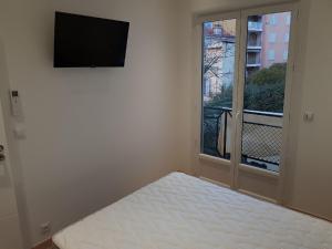 マントンにあるNice Apartment in Menton French Rivieraのベッド、テレビ、窓が備わる客室です。