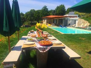 ein langer Tisch mit Teller mit Essen darauf neben einem Pool in der Unterkunft Quinta da Aranha in Arcos de Valdevez