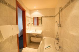 een badkamer met een bad, een wastafel en een douche bij Hotel Rubens in Oostende