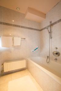 een badkamer met een bad en een douche bij Hotel Rubens in Oostende