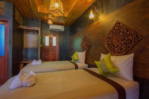 two beds in a room with wooden walls at Sea Rock Resort in Haad Pleayleam