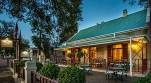 un restaurante con mesas y sillas fuera de un edificio en 88 Baron van Reede Guesthouse, en Oudtshoorn