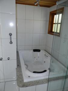 een badkamer met een bad en een douche bij Recanto dos Kerr in Monte Verde