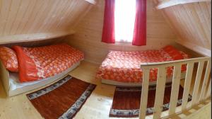 Duas camas num quarto de madeira com cortinas vermelhas em Domki Letniskowe U Cichego em Jezierzany