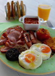 a plate of breakfast food with eggs bacon and sausage at Uisce Beatha House B&B in Portmagee