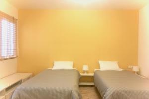 エル・メダノにあるウィー ラブ エル メダノ ハウスの黄色い壁の客室内のベッド2台