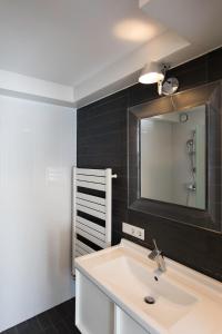 een badkamer met een witte wastafel en een spiegel bij B's Strandappartementen in Domburg