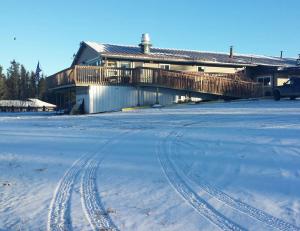 a house with tracks in the snow in front of it at Beluga Lake Lodge in Homer