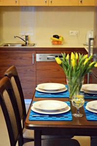 a kitchen table with plates and a vase of flowers on it at Apartament Solano przy plaży in Darlowko