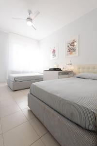 a white bedroom with two beds and a desk at Punta Ala Luxury Villa in Punta Ala