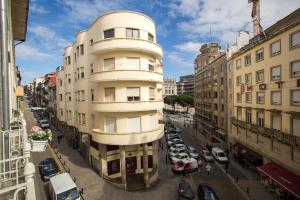 un edificio blanco alto con coches aparcados en una calle en Almada Story Apartments by Porto City Hosts, en Oporto