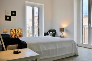 ドンナルカータにあるDonnalucata Ospitalità Diffusaの白いベッドルーム(ベッド1台、椅子、窓付)