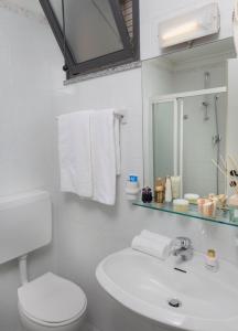 ein Badezimmer mit einem Waschbecken, einem WC und einem Spiegel in der Unterkunft Hotel Piccadilly in Bellaria-Igea Marina