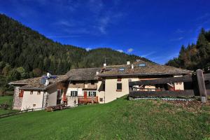 a large white house in a field with a mountain at Maso Toneto in Castello di Fiemme