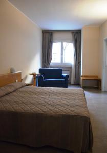 a bedroom with a bed and a blue chair and a window at Borgo Villa Maria in Monticchio