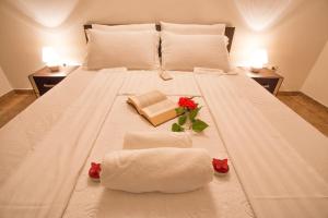 un grande letto bianco con due asciugamani e un libro di Apartment Sun Village Goran a Herceg-Novi