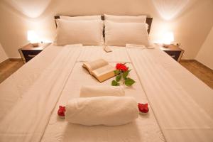 a large white bed with two towels and a book at Apartment Sun Village Goran in Herceg-Novi