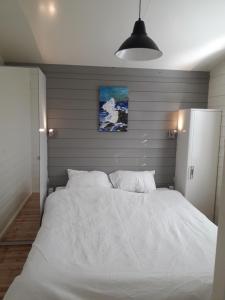 een groot wit bed in een slaapkamer met een muur bij Cozy Cottage in Warmenhuizen