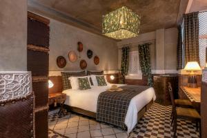 1 dormitorio con cama y lámpara de araña en Riad Karmela Princesse, en Marrakech