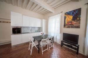 uma cozinha com uma mesa e cadeiras e uma televisão em Appartamento i Priori em Volterra