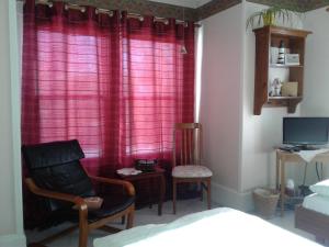 een slaapkamer met rode gordijnen en een stoel en een bed bij B&B Art of Germany in Caledonia