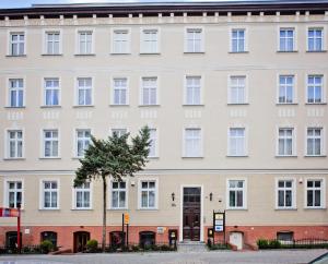 um grande edifício branco com uma árvore em frente em Apartamenty Retro em Poznań