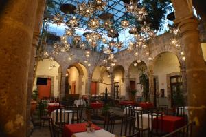 uma sala de jantar com mesas, cadeiras e lustres em Hotel Alameda Centro Historico em Morelia