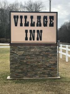 a sign for a village inn on a brick wall at Village Inn in Lovingston
