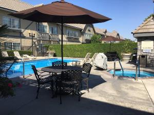 a table with chairs and an umbrella next to a pool at Folk Inn Ontario Airport in Ontario +19 photos