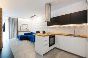 cocina con armarios blancos y sofá azul en Super-Apartamenty Luxury, en Poznan
