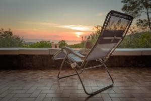 einen Stuhl auf einer Terrasse mit Blick auf den Sonnenuntergang im Hintergrund in der Unterkunft Punta Ala Luxury Villa in Punta Ala