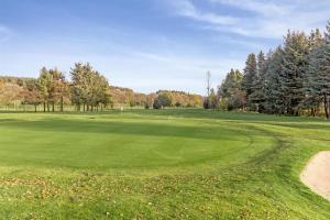 a golf course with a green field and trees at The View Deer Park Luxury Apartment in Edinburgh