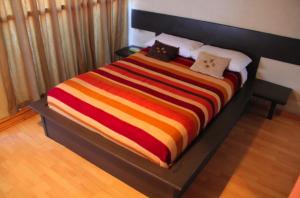 a large bed with a colorful striped blanket on it at Hotel Miramar - La Paz in La Paz