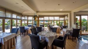 a restaurant with white tables and chairs and windows at Hotel De Kommel in Voeren