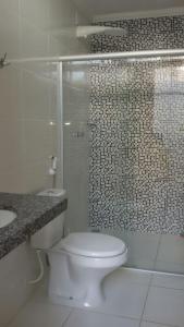 uma casa de banho com um WC e uma cabina de duche em vidro. em Apto em Porto Seguro - Centro em Porto Seguro