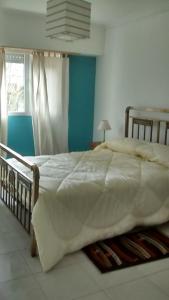 Un dormitorio con una cama grande con un edredón blanco. en Departamentos R y R Azcuénaga, en Tandil