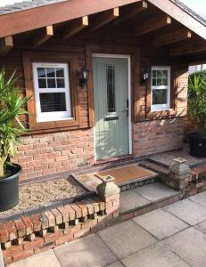 a house with a porch and a window at Boutique Garden Lodge @ The Larches in Wolverhampton