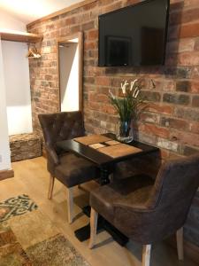 a dining room with a table and chairs and a tv on a brick wall at Boutique Garden Lodge @ The Larches in Wolverhampton