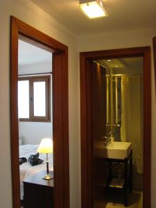 y baño con cama, lavabo y espejo. en Apartamentos Cardinal Bariloche en San Carlos de Bariloche