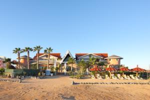 a beach with houses and umbrellas and palm trees at Residencial Cabo Verde Palace in Santa Maria